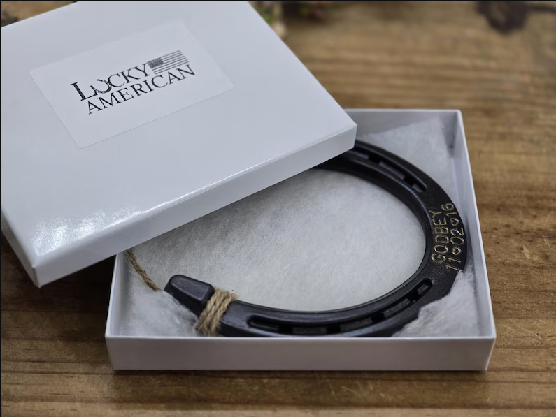 Real horseshoe painted an oil-rubbed bronze color and engraved with a last name and date. Displayed in a gift box.