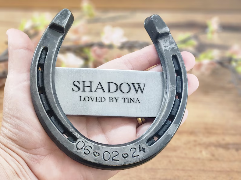 Real horseshoe with horse's name and 'LOVED BY' engraved on a center metal piece welded to the back of the shoe. Engraved with date of passing along the bottom.