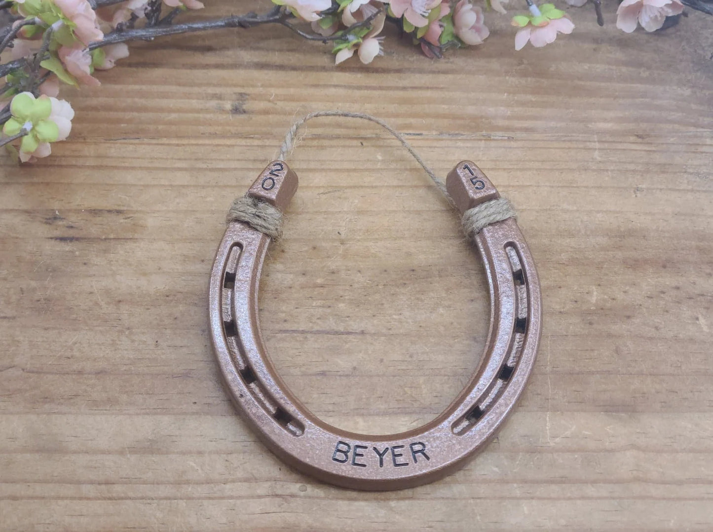 Real horseshoe painted copper with a name stamped along the bottom and a year in the upper corners of the horseshoe.