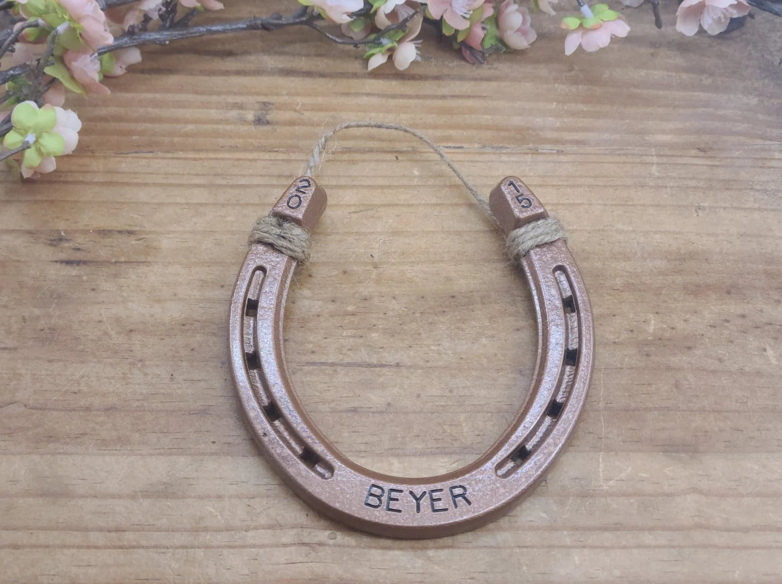 Real horseshoe painted copper with a name stamped along the bottom and a year in the upper corners of the horseshoe.