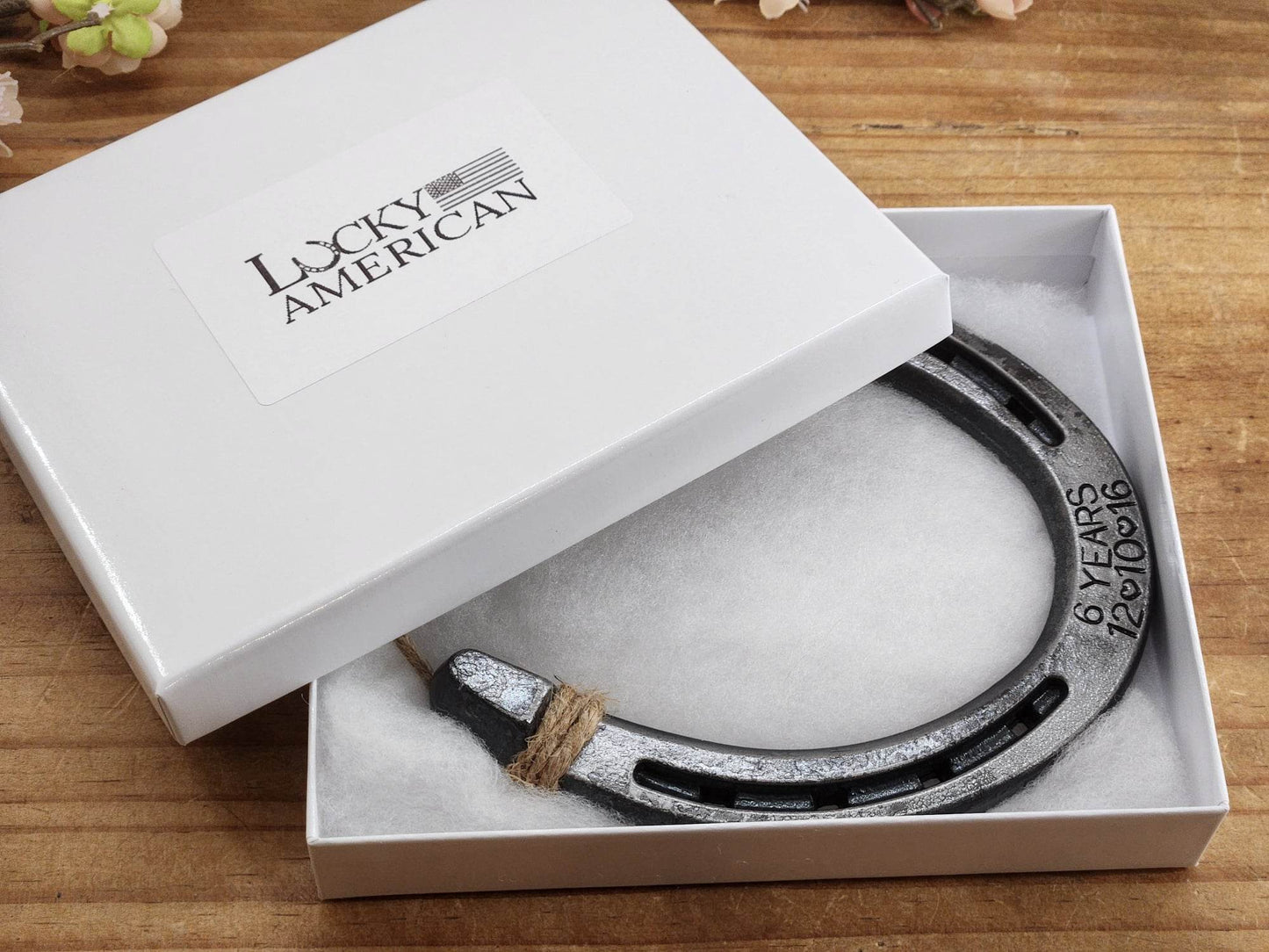Real horseshoe engraved with '6 YEARS' plus an anniversary date along the bottom toe portion of the horseshoe. Displayed in a gift box.