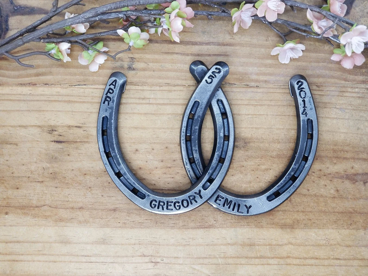 Two real horseshoes welded together and personalized with names along the bottom of each horseshoe and a date along the top areas.