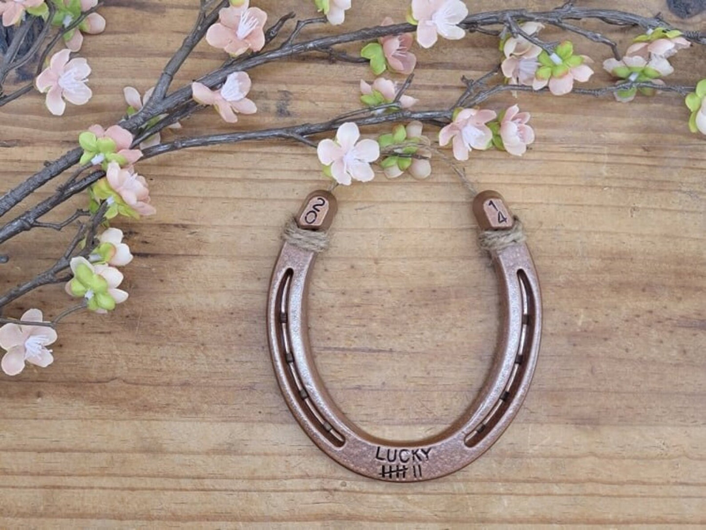 Real horseshoe painted copper and stamped with the word 'LUCKY' plus 7 tally marks along the bottom and the year in the upper corners of the horseshoe.