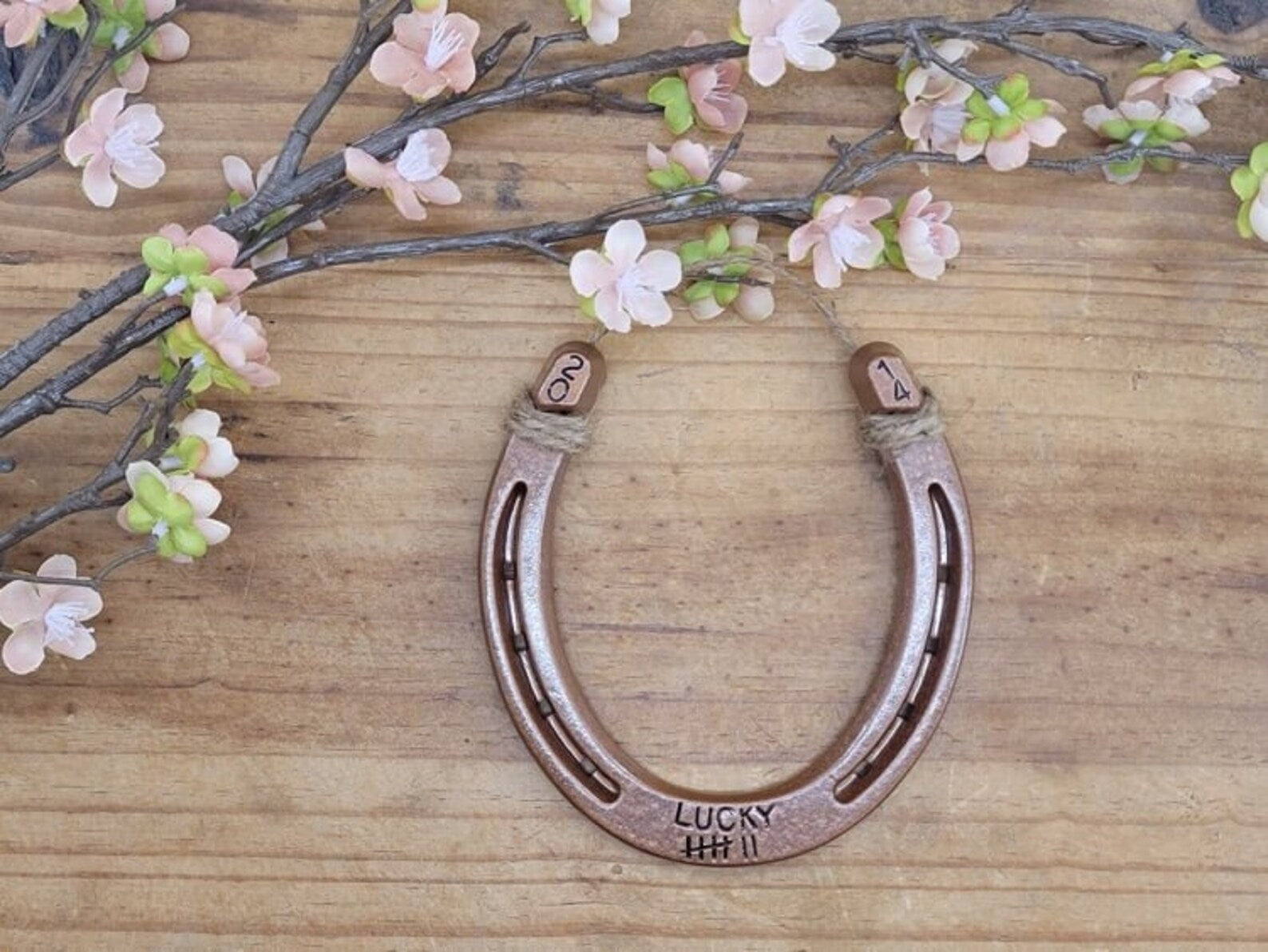 Real horseshoe painted copper and stamped with the word 'LUCKY' plus 7 tally marks along the bottom and the year in the upper corners of the horseshoe.