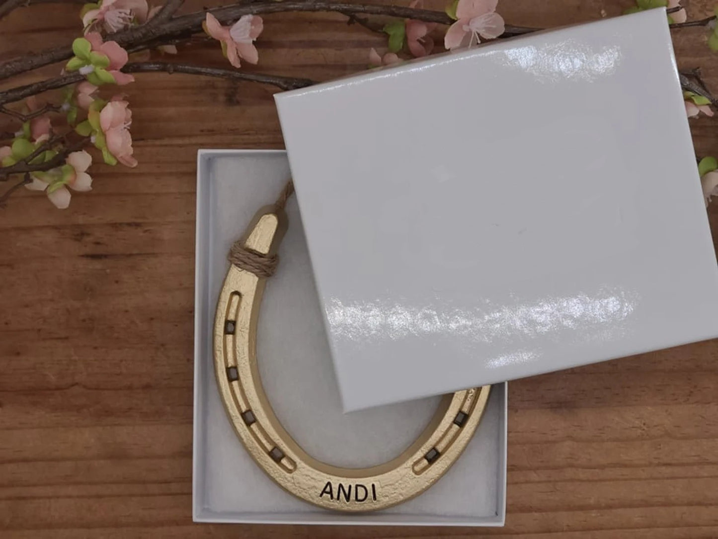 Real horseshoe painted gold and personalized with a name along the bottom. Displayed in a gift box.