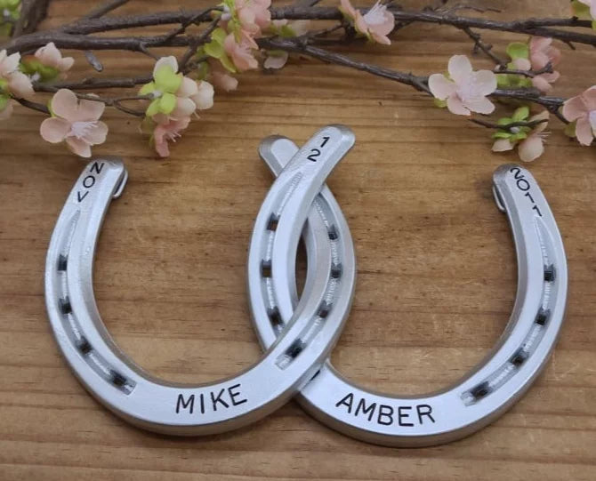 Real horseshoes painted aluminum color and welded together. Personalized with names along the bottom and date at the top. Designed to hang on a wall.