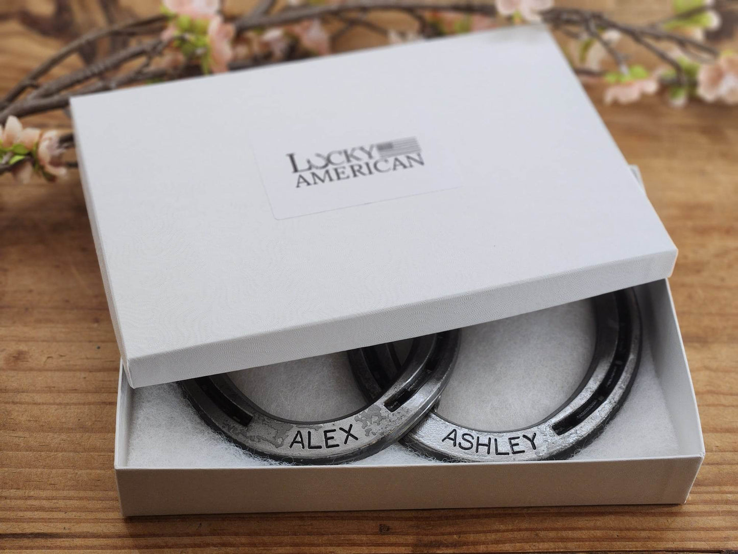 Two real horseshoes welded together and personalized with names along the bottom of each horseshoe. Displayed in a gift box.