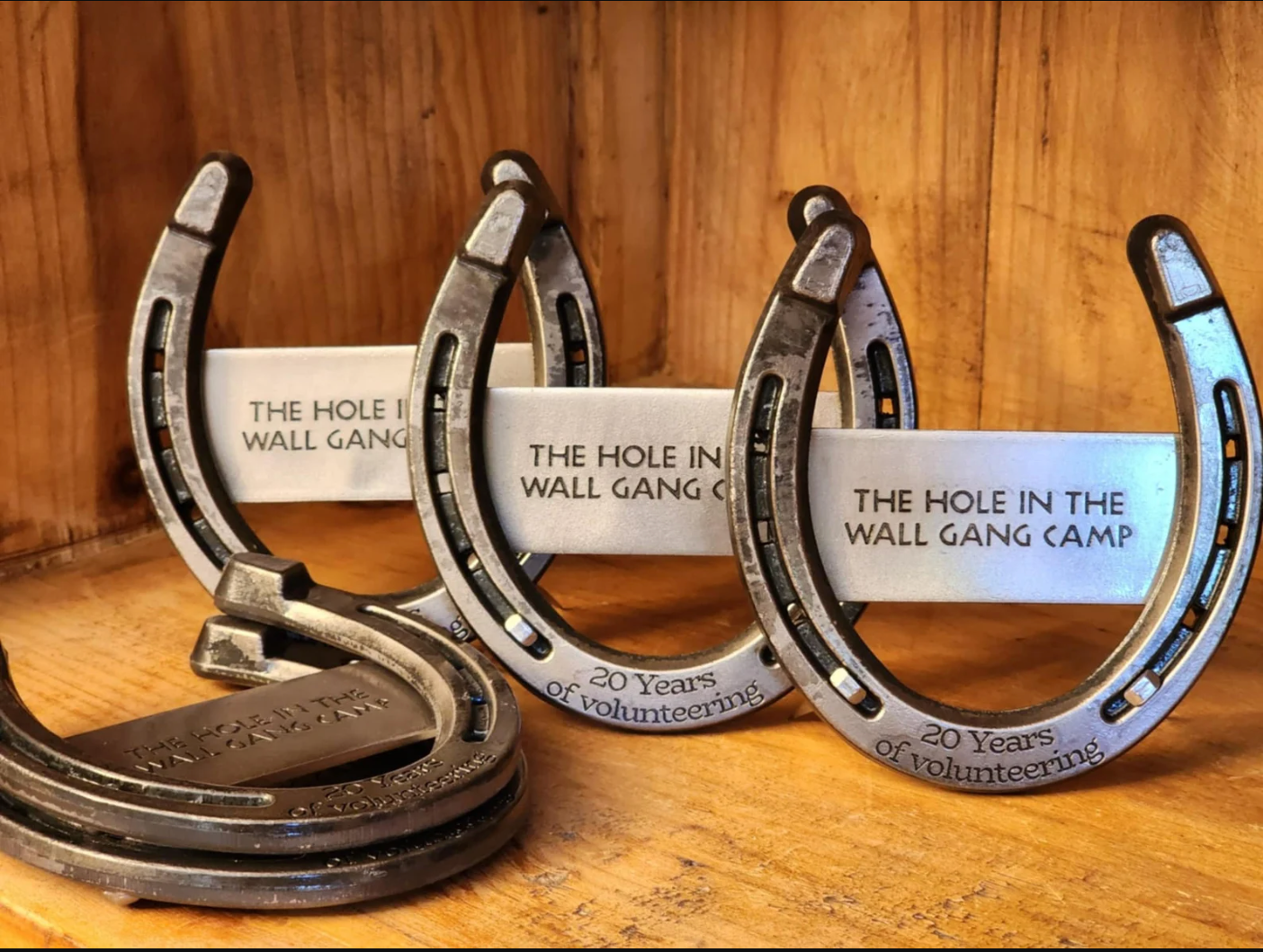 Real horseshoes with a company logo engraved on a metal plaque welded to the back of the horseshoe. Text is engraved along the bottom pertaining to the company.