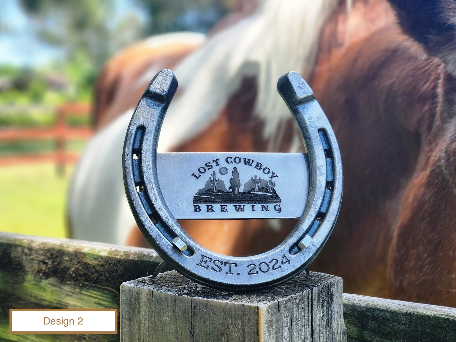 Real horseshoe with a custom corporate logo engraved on a center metal plaque and welded to the horseshoe. Additional details about the company engraved along the toe of the horseshoe. Background image is a paint horse.