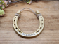 Decorative horseshoe painted gold and stamped with WELCOME along the bottom. Jute string attached at the top for hanging.