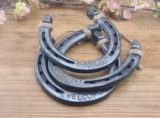 3 real separate horseshoes stacked over each other. One horseshoe reads 'WELCOME'. One horseshoe reads 'HOME SWEET HOME' and one horseshoe reads 'BLESS OUR HOME'