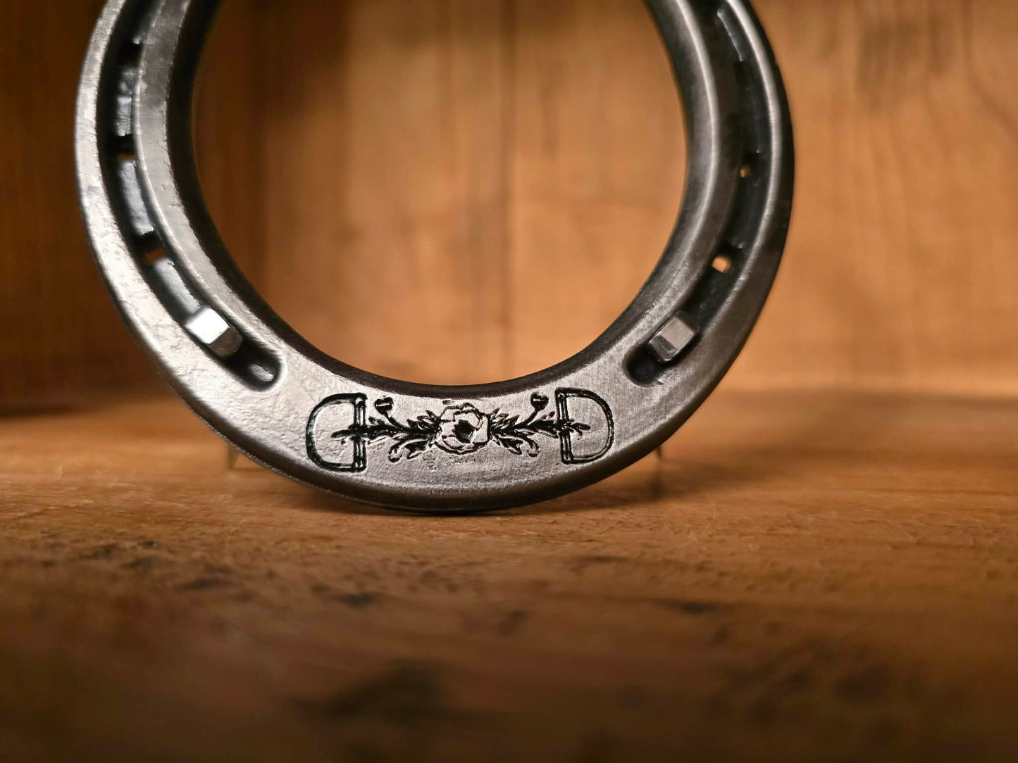 Real metal horseshoe engraved along the toe with a logo of a horse bit and flower