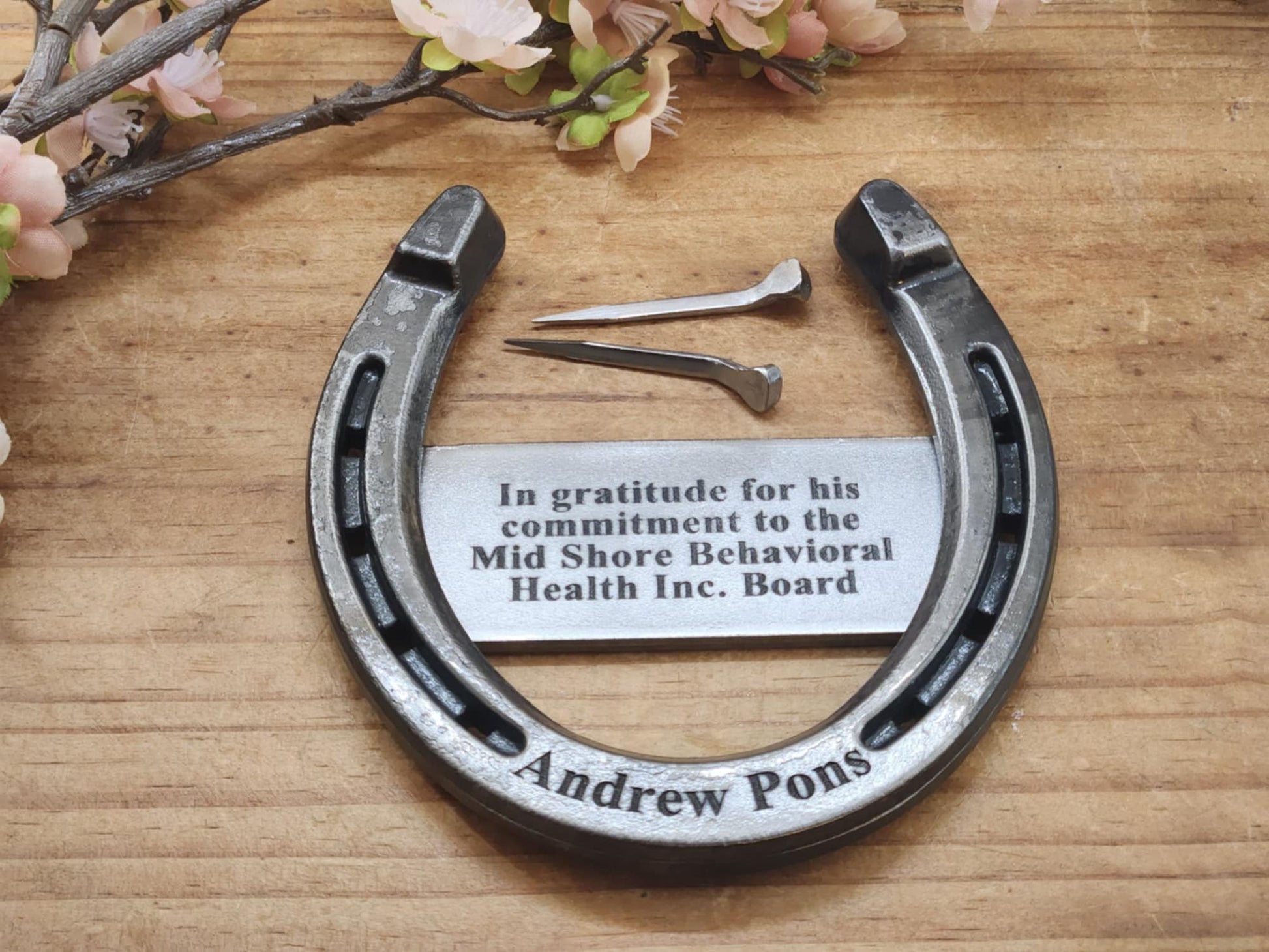 Real horseshoe engraved with a special message on a metal plaque and the person's name along the bottom. Pictured with horseshoe nails for displaying.