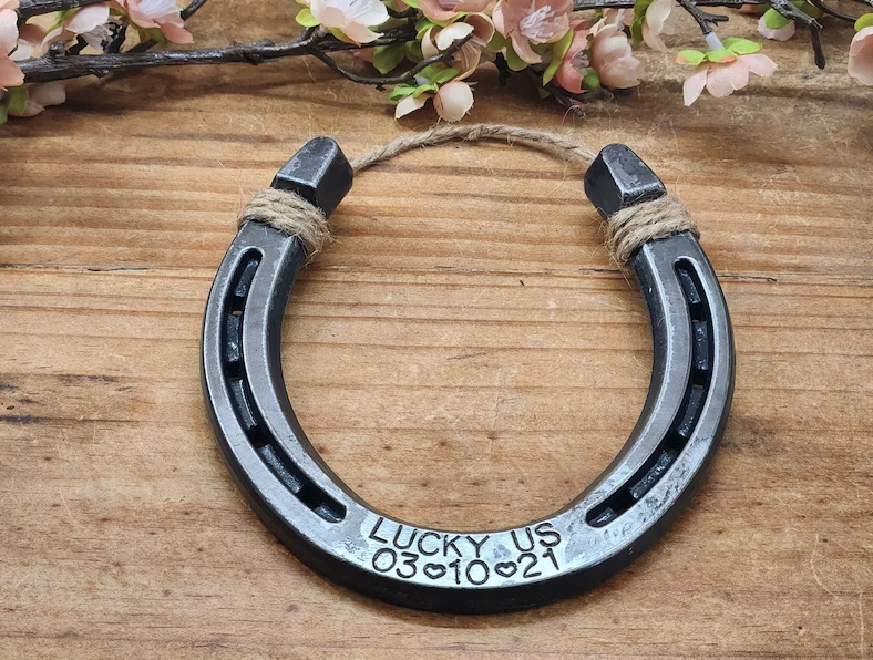 Real horseshoe stamped with 'LUCKY US' along the bottom and customized with an anniversary date. Jute string attached to the top for hanging.