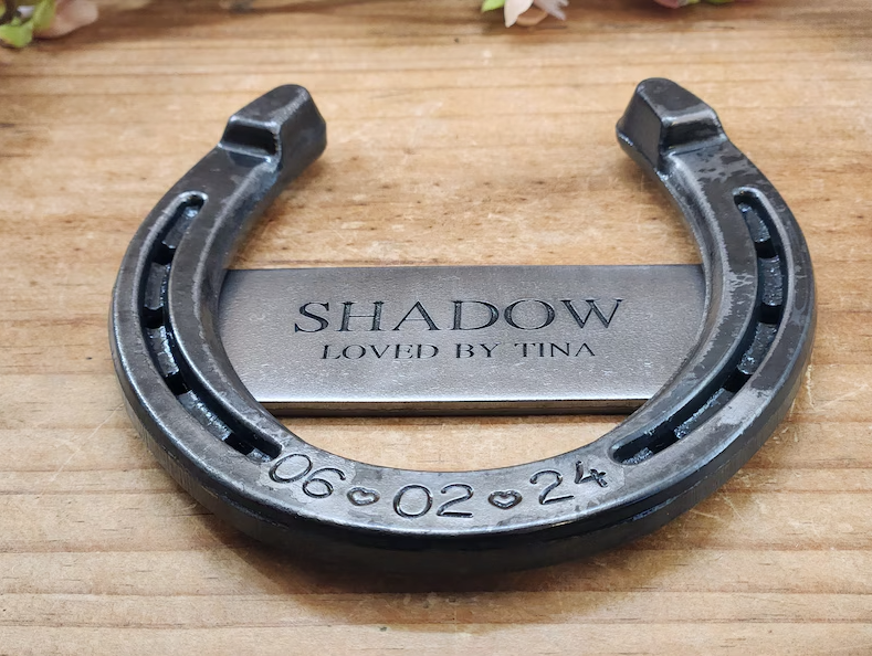 Real horseshoe with horse's name and 'LOVED BY' engraved on a center metal plaque welded to the back of the shoe. Engraved with date of passing along the bottom.