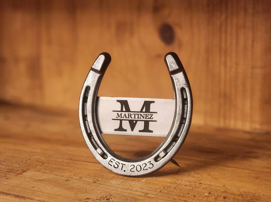 Real horseshoe with custom monogram in the center and the anniversary year engraved along the bottom of the horseshoe. Displayed freestanding with horseshoe nails.