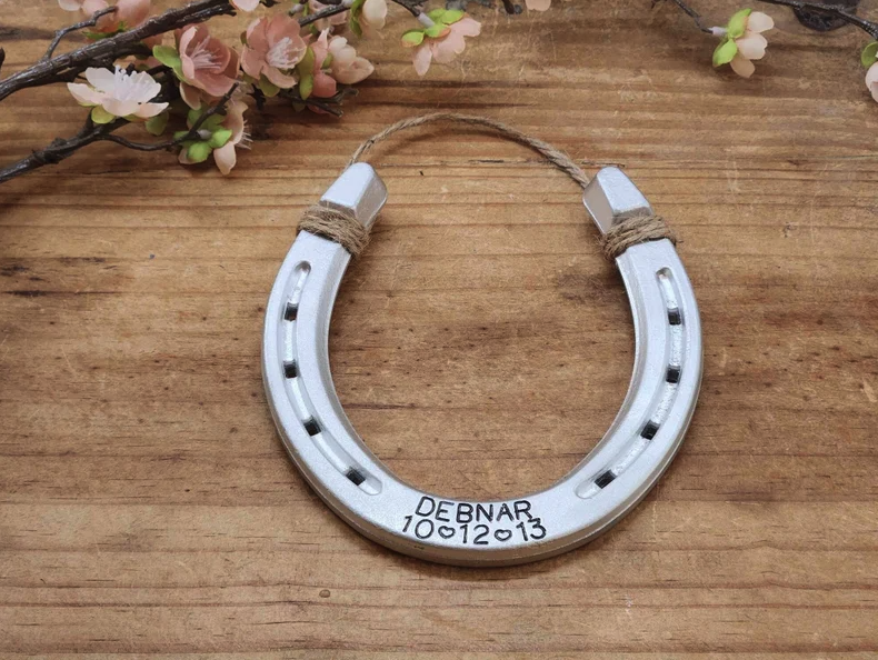 Real horseshoe painted an aluminum color to represent the traditional gift for ten year anniversaries. Customized with hand-stamped name and date along the bottom.