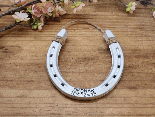 Real horseshoe painted an aluminum color to represent the traditional gift for ten year anniversaries. Customized with hand-stamped name and date along the bottom.