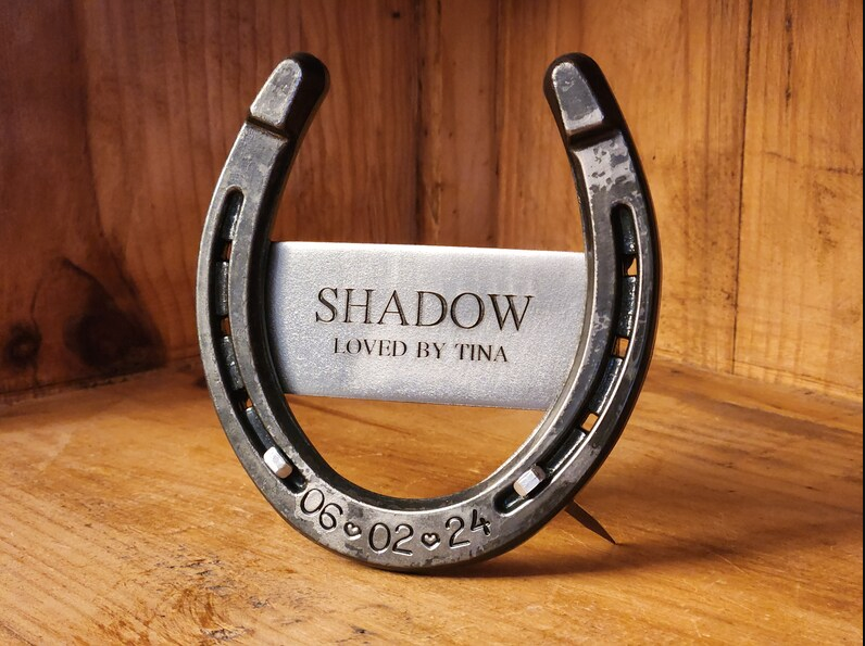 Real horseshoe with horse's name and 'LOVED BY' plus the owner's name engraved on a center metal plaque welded to the back of the shoe. Engraved with date of passing along the bottom.