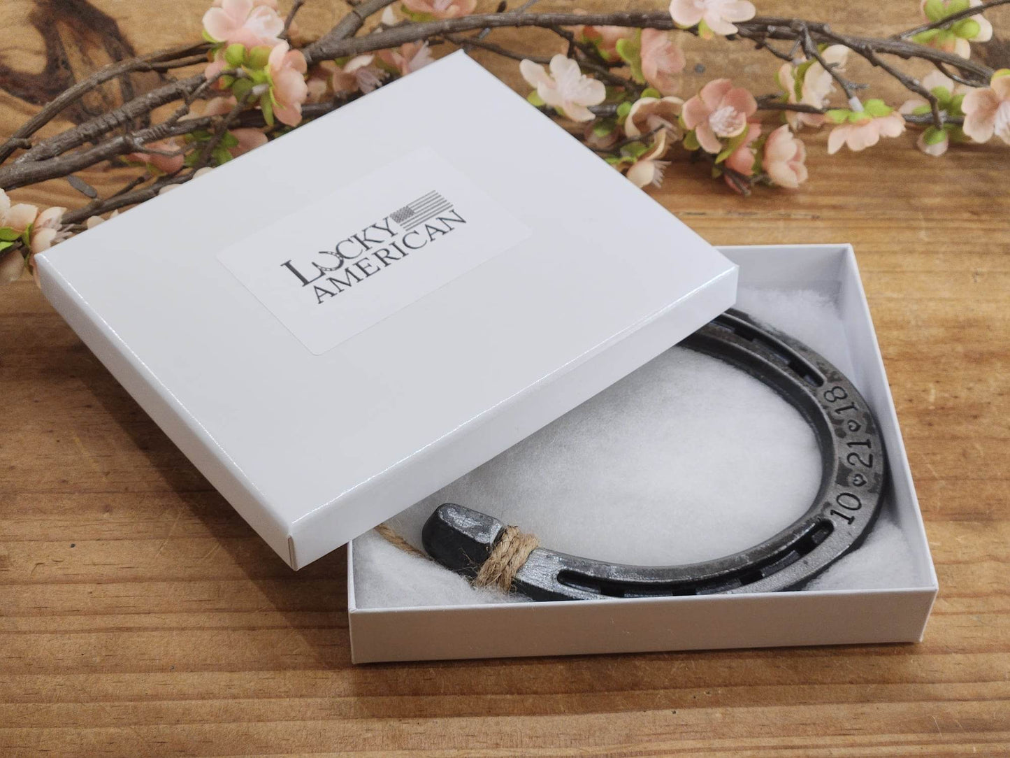 Real lucky horseshoe in a white gift box with a date stamped along the toe of the horseshoe.