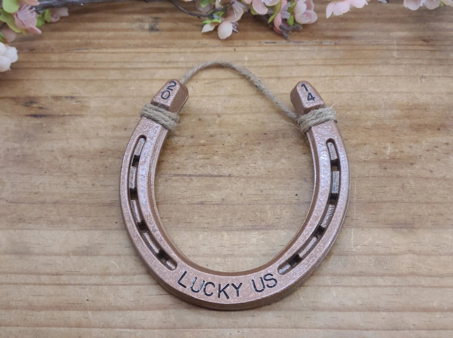 Real horseshoe painted copper with the words 'LUCKY US' stamped along the bottom and the year in the upper corners of the horseshoe.
