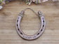 Real horseshoe painted copper with the words 'LUCKY US' stamped along the bottom and the year in the upper corners of the horseshoe.