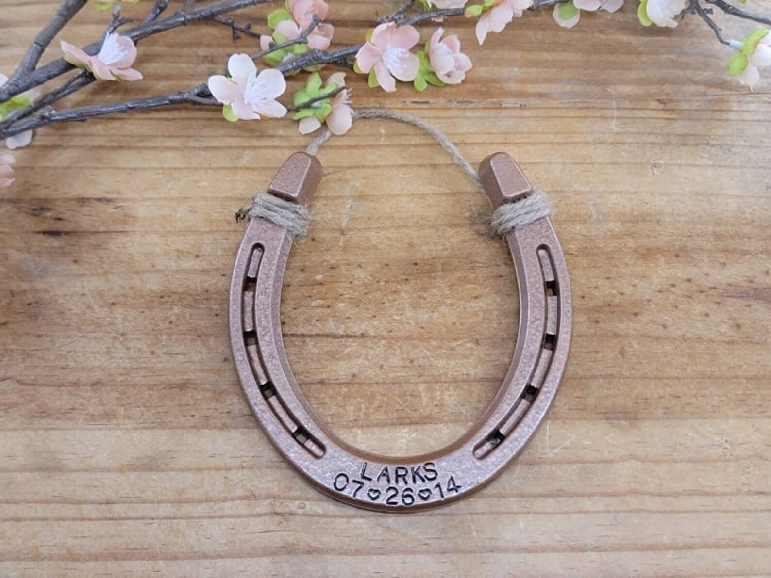 Real horseshoe painted copper with two lines of personalization. Pictured with a last name and a date stamped along the bottom of the horseshoe.